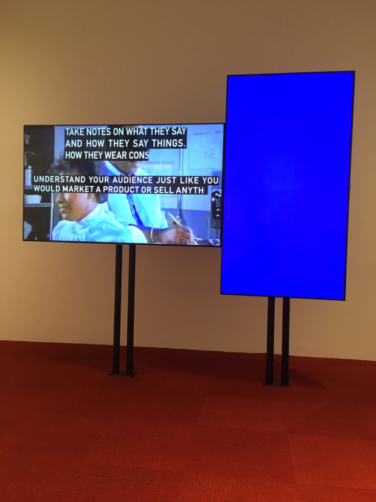 a video installation in an art gallery with two video screens, one horizontal and one vertical